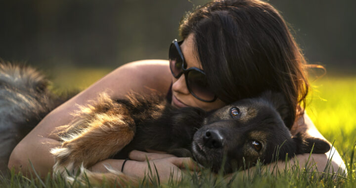 Woman hugging her dog in the grass